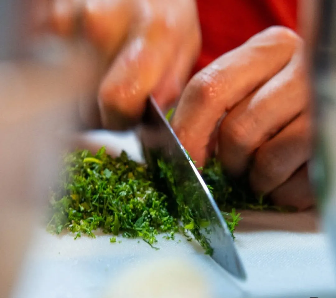 Manos del chef picando hierbas frescas con un cuchillo